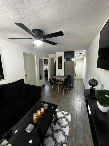a living room with a black couch and a ceiling fan at Departamento en Torres Reyes ll in Tijuana