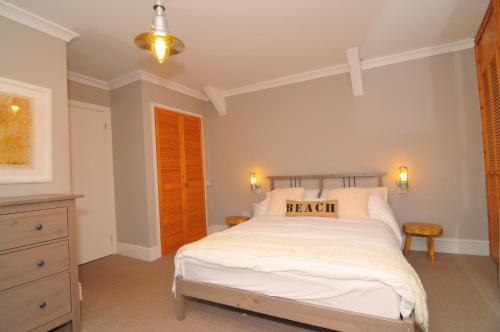 a bedroom with a bed with a pillow that reads beach at 2 Castle Hall Llangrannog in Llangranog