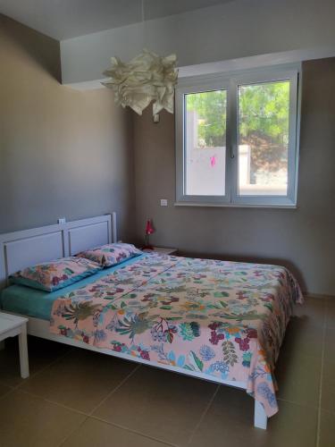 a bedroom with a bed with a comforter and two windows at Ferienwohnung direkt am Strand in Ierapetra