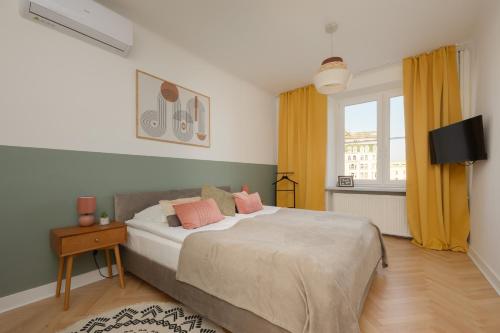 a bedroom with a bed with pink pillows on it at Apartment for 6 people near Royal Baths Park by Renters Prestige in Warsaw