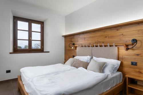 a bedroom with a white bed with a wooden headboard at Tuscany Living - Terra Antica in Montepulciano