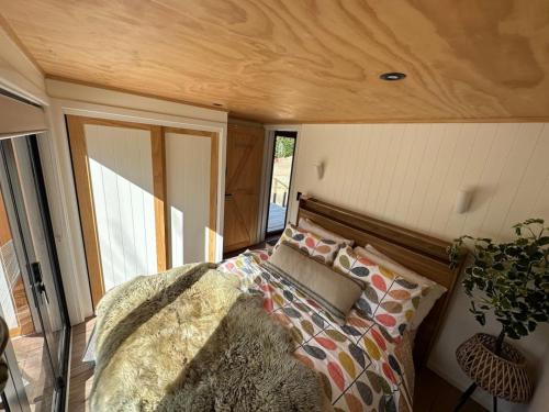 a bedroom with a bed and a wooden ceiling at Petite Perfection tiny house at Lake Hawea in Lake Hāwea