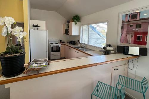 a kitchen with a counter with a refrigerator and two chairs at Character on Capell large house perfect for extended family in Lake Hawea