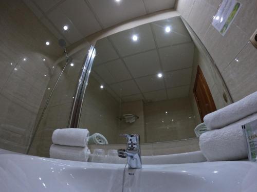 a bathroom with a sink with a mirror and towels at Hotel Saylu in Granada