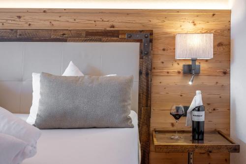 Cama con almohada y mesa con lámpara en Hotel Bergkristall en Silbertal