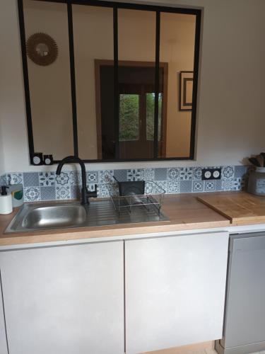 - un comptoir de cuisine avec un évier et un miroir dans l'établissement Maison de famille, à Saint-Julien-de-Cassagnas