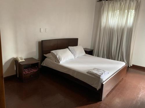1 dormitorio con 1 cama grande con sábanas blancas y ventana en Hotel el regidor, en Buga
