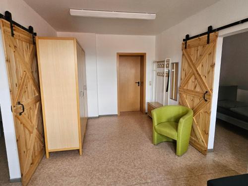 Zimmer mit zwei Türen und einem grünen Stuhl in der Unterkunft Gästehaus Bad Dürrenberg in Bad Dürrenberg