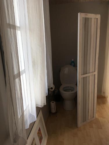 a bathroom with a toilet and a open door at Chambre grise in Barbâtre