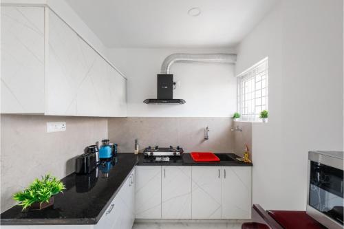 a kitchen with white cabinets and a black counter top at Olive Serviced Apartments BTM Layout in Bengaluru