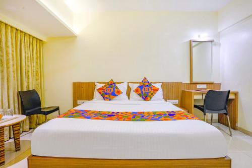 a bedroom with a large bed with chairs and a table at FabExpress Kuber in Navi Mumbai