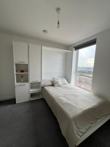 Habitación blanca con cama y ventana en Private ensuite room near London en Dagenham