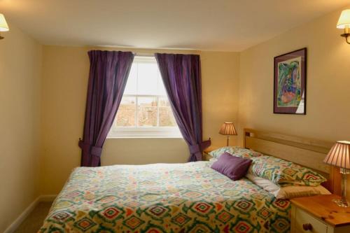 Schlafzimmer mit einem Bett und einem Fenster mit lila Vorhängen in der Unterkunft 9 Golden Street, Deal in Deal