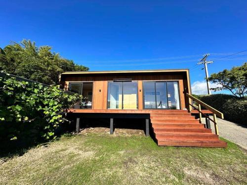 a small house with wooden stairs and windows at Henley - Omori Holiday Home in Kuratau