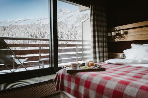a hotel room with a bed and a window with a view at Hôtel Alpen Ruitor in Méribel
