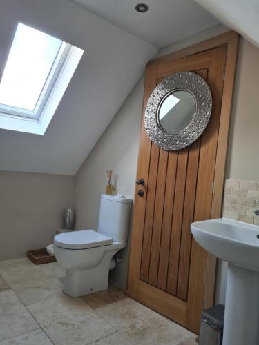 a bathroom with a toilet and a wooden door at The Cartshed, Coltishall, Norfolk in Norwich