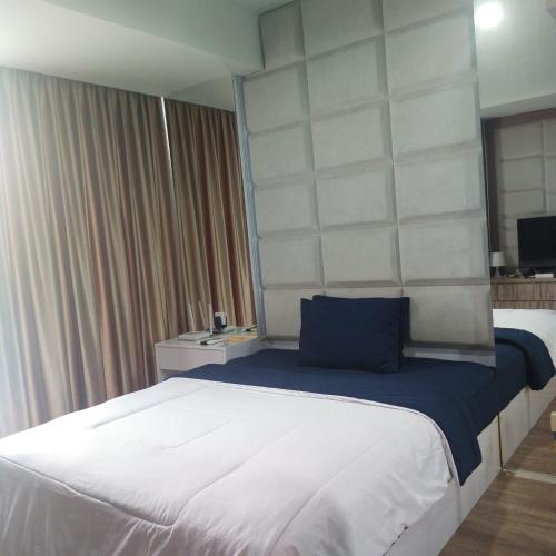 a bedroom with a large bed with a blue pillow at Apartemen Skylounge Balikpapan 2BR in Sepinggang-besar