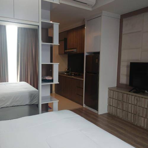 pokój hotelowy z łóżkiem i telewizorem oraz sypialnią w obiekcie Apartemen Skylounge Balikpapan 2BR w mieście Sepinggang-besar