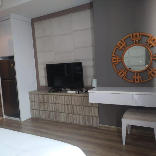 a room with a television and a mirror on the wall at Apartemen Skylounge Balikpapan 2BR in Sepinggang-besar