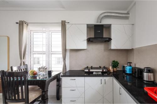 a kitchen with white cabinets and a black counter top at Olive Serviced Apartments BTM Layout in Bengaluru