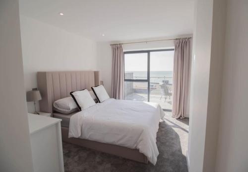 a bedroom with a bed and a large window at Marine View Apartment By Air Premier in Seaford