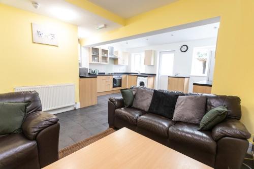 a living room with two leather couches and a kitchen at April Disc - Long Stay - Contractors in Bristol