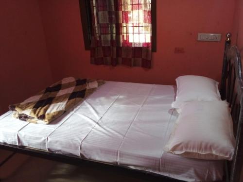 - un lit avec des draps et des oreillers blancs dans l'établissement Honnavar homestays, à Honāvar