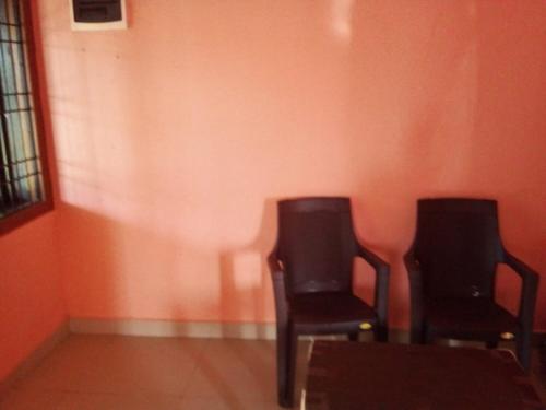 2 chaises assises dans une pièce avec un mur orange dans l'établissement Honnavar homestays, à Honāvar