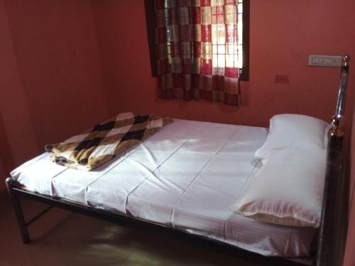 Ce petit lit se trouve dans un dortoir doté de draps blancs. dans l'établissement Honnavar homestays, à Honāvar