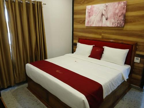 a bedroom with a large bed with white and red pillows at Ramraj Resort in Kanyakumari