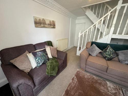a living room with two couches and a staircase at Scotch Terrace - 3 Bedrooms - Sleeps 6 in Whitehaven