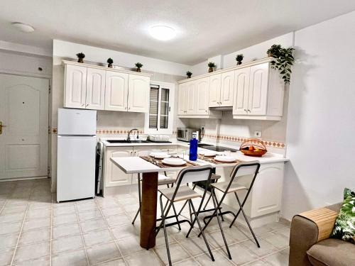 a kitchen with white cabinets and a table and chairs at Piera's Apartment in Chayofa