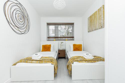 two beds in a room with white walls at Newly refurbished 2BR wbalcony in Vibrant Peckham in London