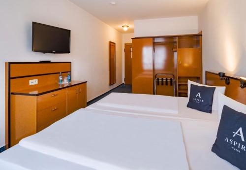 a hotel room with two beds and a flat screen tv at Aspire Frankfurt Airport, Trademark Collection by Wyndham in Rüsselsheim