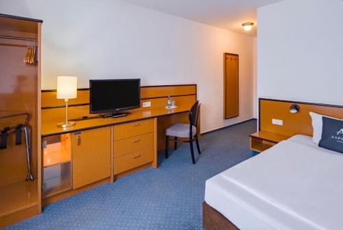 a hotel room with a bed and a desk with a television at Aspire Frankfurt Airport, Trademark Collection by Wyndham in Rüsselsheim