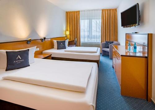 a hotel room with two beds and a television at Aspire Frankfurt Airport, Trademark Collection by Wyndham in Rüsselsheim