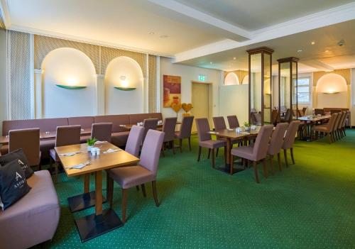 a restaurant with wooden tables and purple chairs at Aspire Frankfurt Airport, Trademark Collection by Wyndham in Rüsselsheim