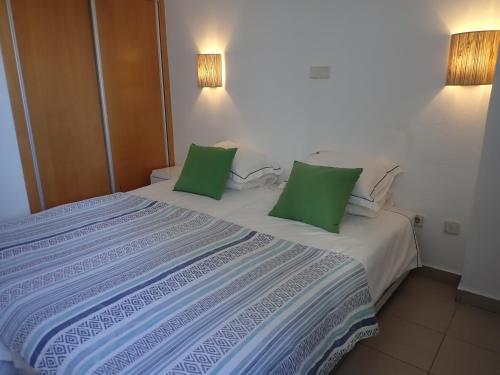 a large bed with two green pillows on it at Great value 5 mins to Praia de Rocha beach in Portimão