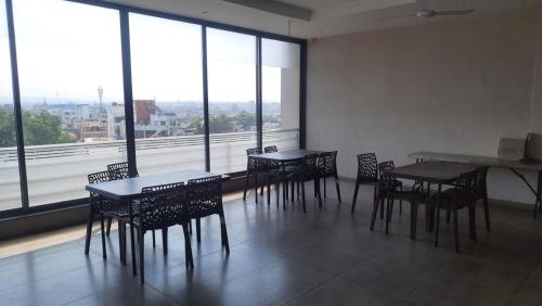 a room with tables and chairs and a large window at Hotel Elite Inn- In Front Of Railway Station in Kolhapur