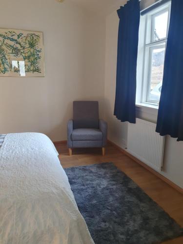 um quarto com uma cama, uma cadeira e uma janela em Vorsabær Apartment em Selfoss