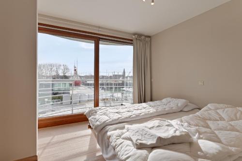 Duas camas num quarto com uma janela grande em Harbour View 2a 2ev em Zeebrugge