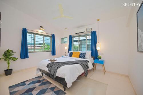 a bedroom with a large bed with blue curtains at EKOSTAY - Alpha Villa in Igatpuri