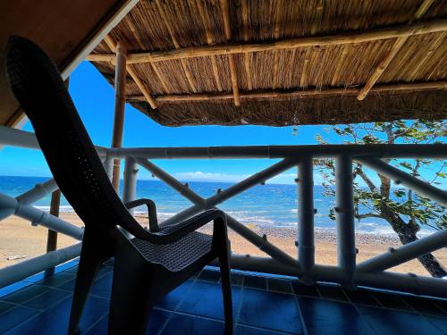 a chair on a balcony with a view of the beach at AoJing Diving Resort澳鲸潜水温泉店 in Dauin