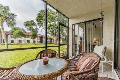 a patio with a table and chairs and a large window at MyCataleya Comfy Condo near Beach (Bradenton) in Bradenton