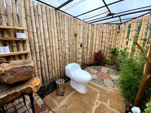 a toilet in a garden with a wooden fence at Iraca Glamp in Santa Sofía