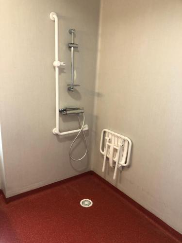 une douche dans une salle de bain avec un sol rouge dans l'établissement Les logis de Simon, à La Flotte