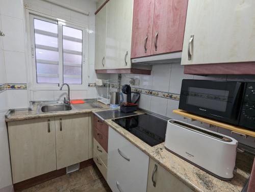 une petite cuisine avec un évier et un micro-ondes dans l'établissement Apartamento Delfin San Juan, à Alicante