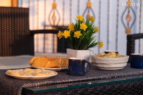 a table with a plate of bread and a vase of flowers at EKOSTAY - Alpha Villa in Igatpuri