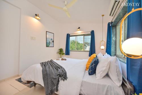 a bedroom with a white bed with pillows and a window at EKOSTAY - Alpha Villa in Igatpuri