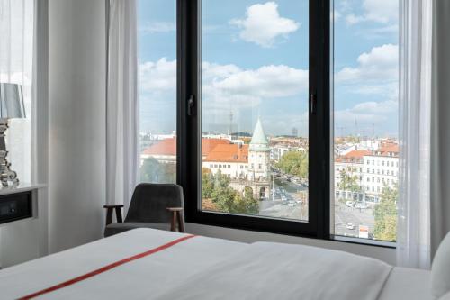 a bedroom with a bed and a view of a city at Ruby Lilly Hotel Munich in Munich